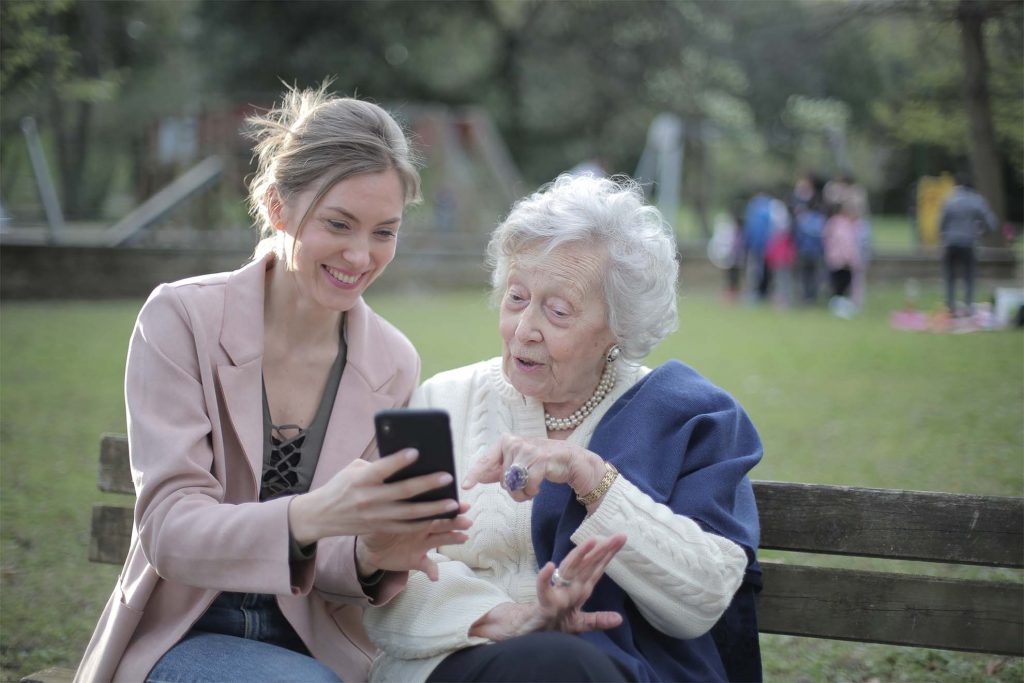 older lady sitting on bench with younger lady 