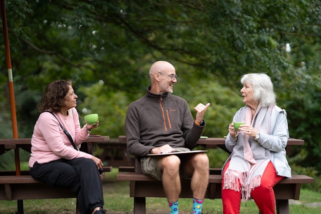 Group sitting outside drinking coffee on a bench